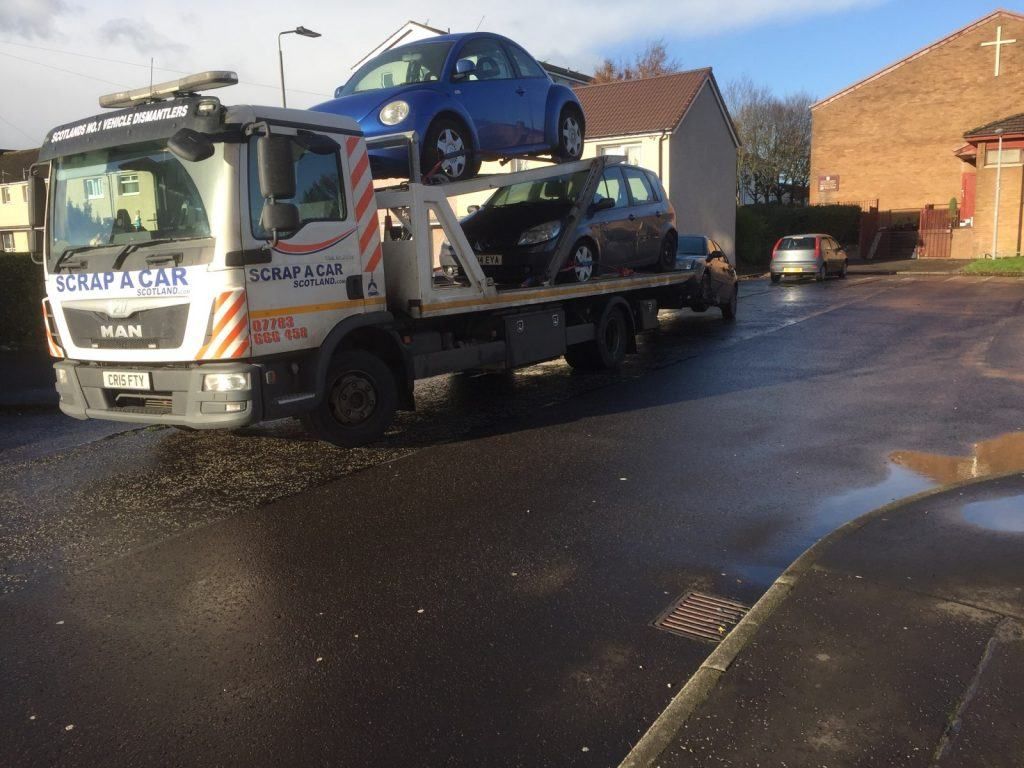 Recovery truck winching a non-running classic Beetle onto the bed for scrapping
